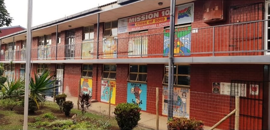 The two-storey red-brick classroom block at Belverton Secondary School, with painted murals along the ground floor